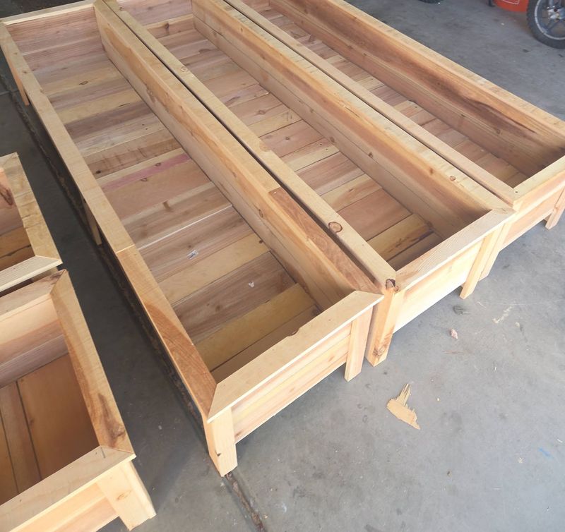 Three long cedar planters side by side on a garage floor